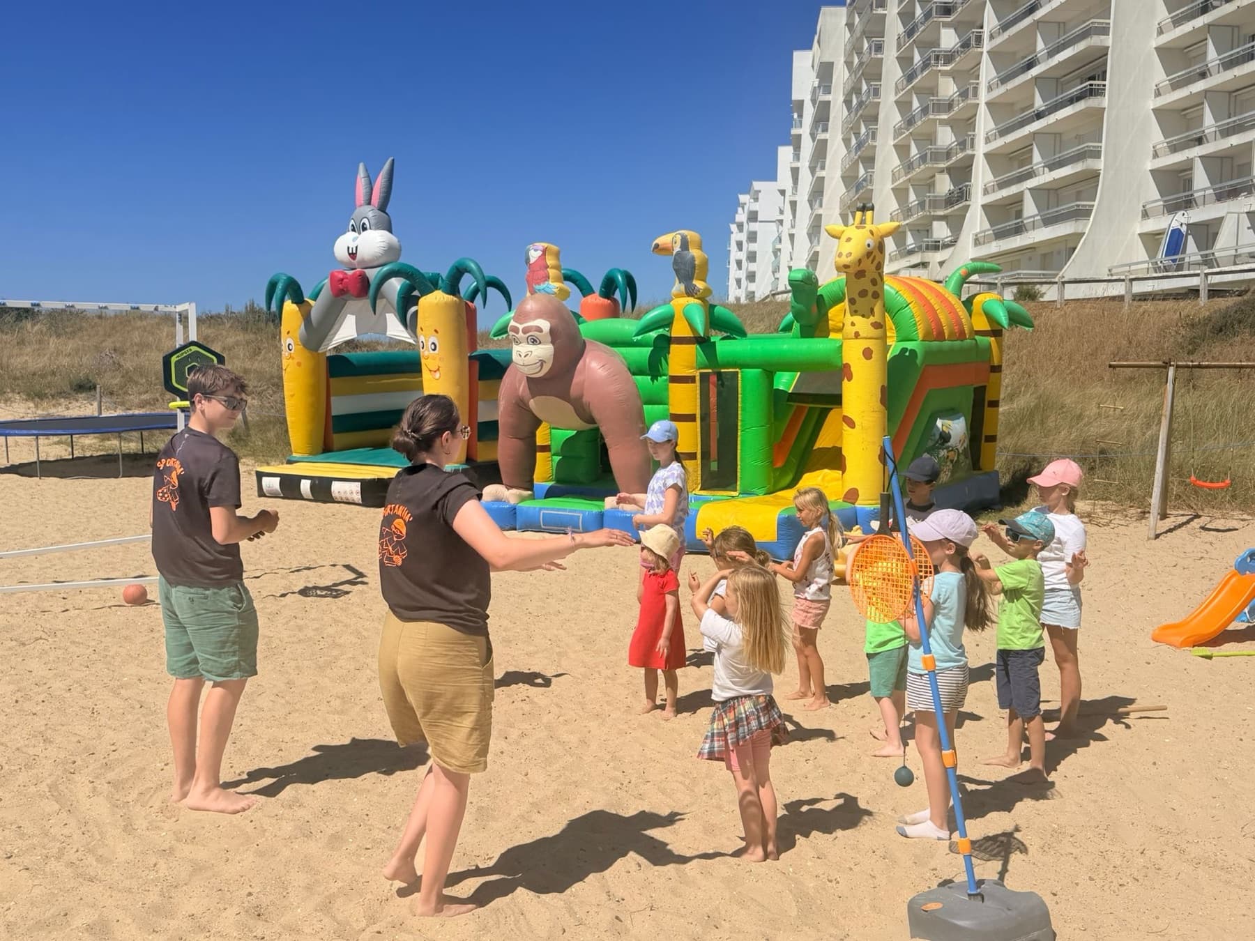 Animation gonflable sur la plage devant une résidence de vacances.