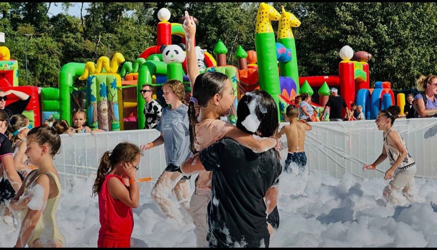 Enfants dans une mousse party avec structure gonflable lors d'une animation scolaire.