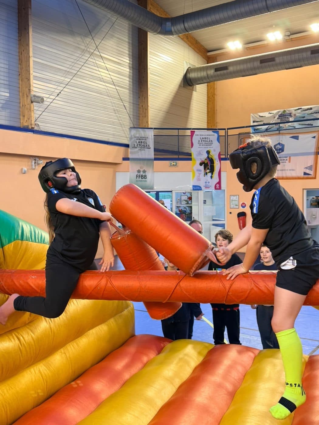 Duel de joute gonflable entre deux participants casqués.